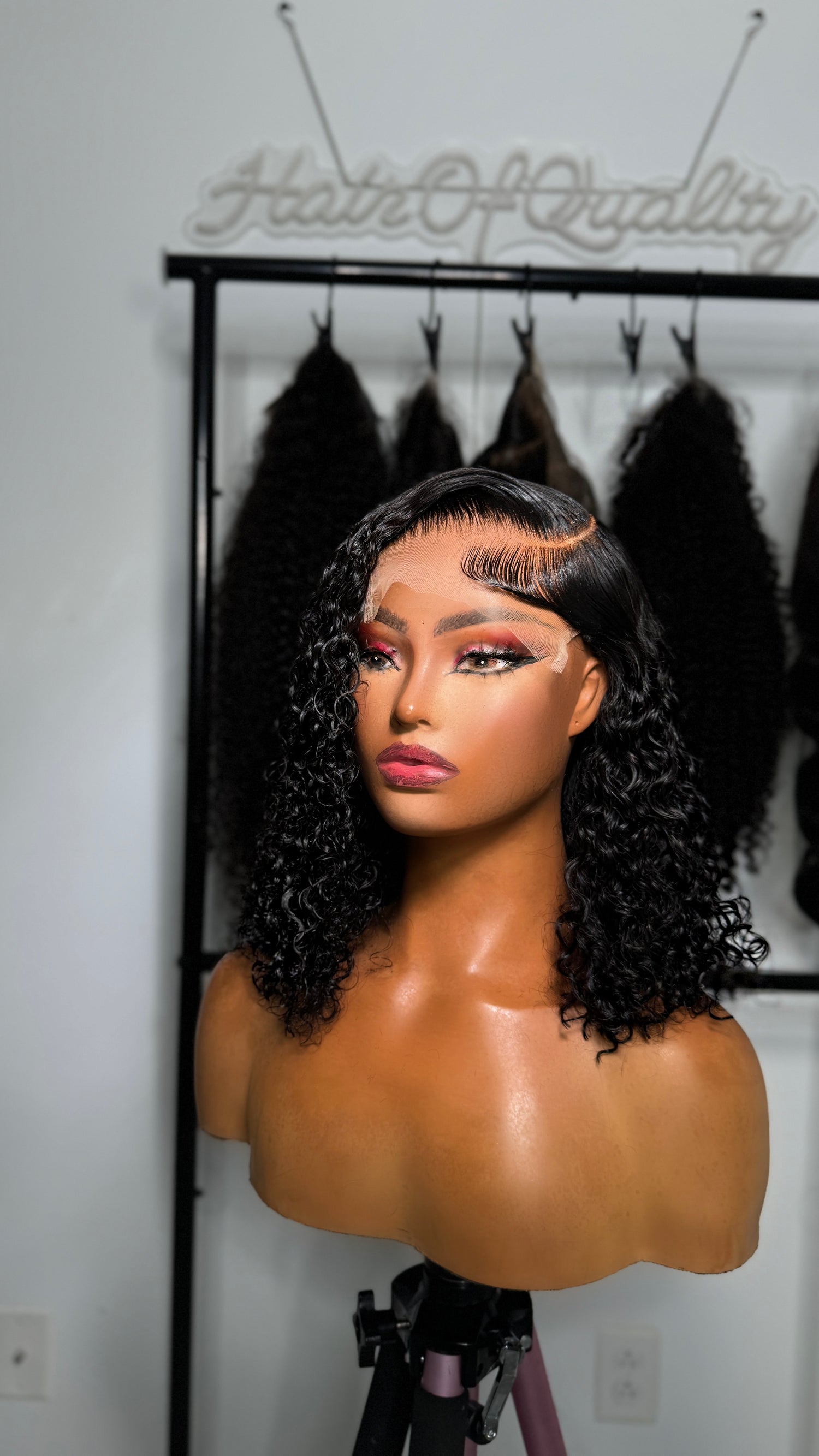 A mannequin head with a curly, shoulder-length wig styled in a deep side part is displayed